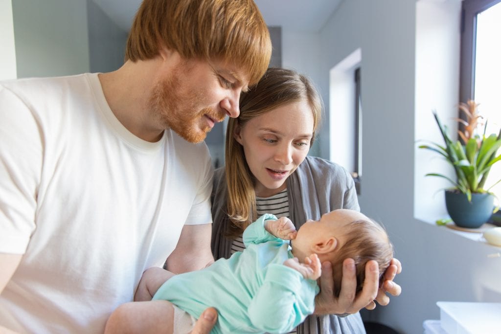 New mother and father cuddling and talking to baby