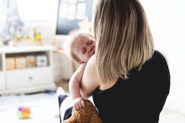 Back of a mom carrying a crying baby